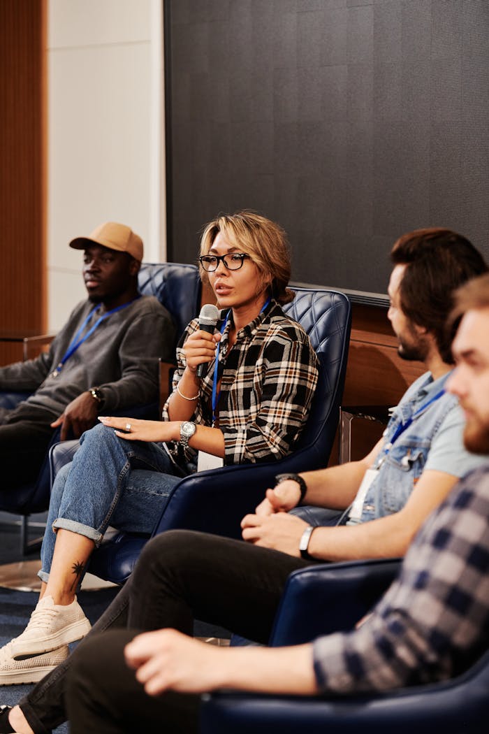 impact-img A diverse group of adults engaged in a panel discussion during a business seminar. Indoors setting.
